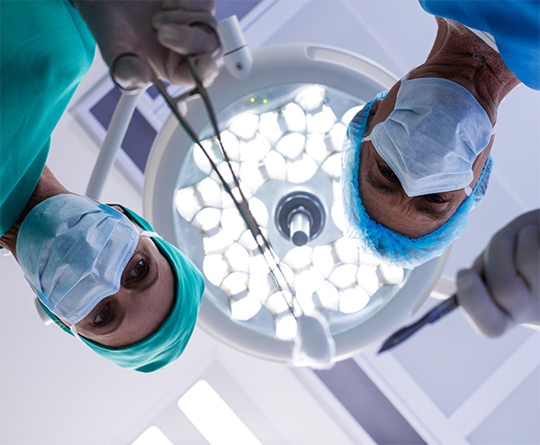 Médicos con indumentaria quirúrgica bajo la iluminación del quirófano